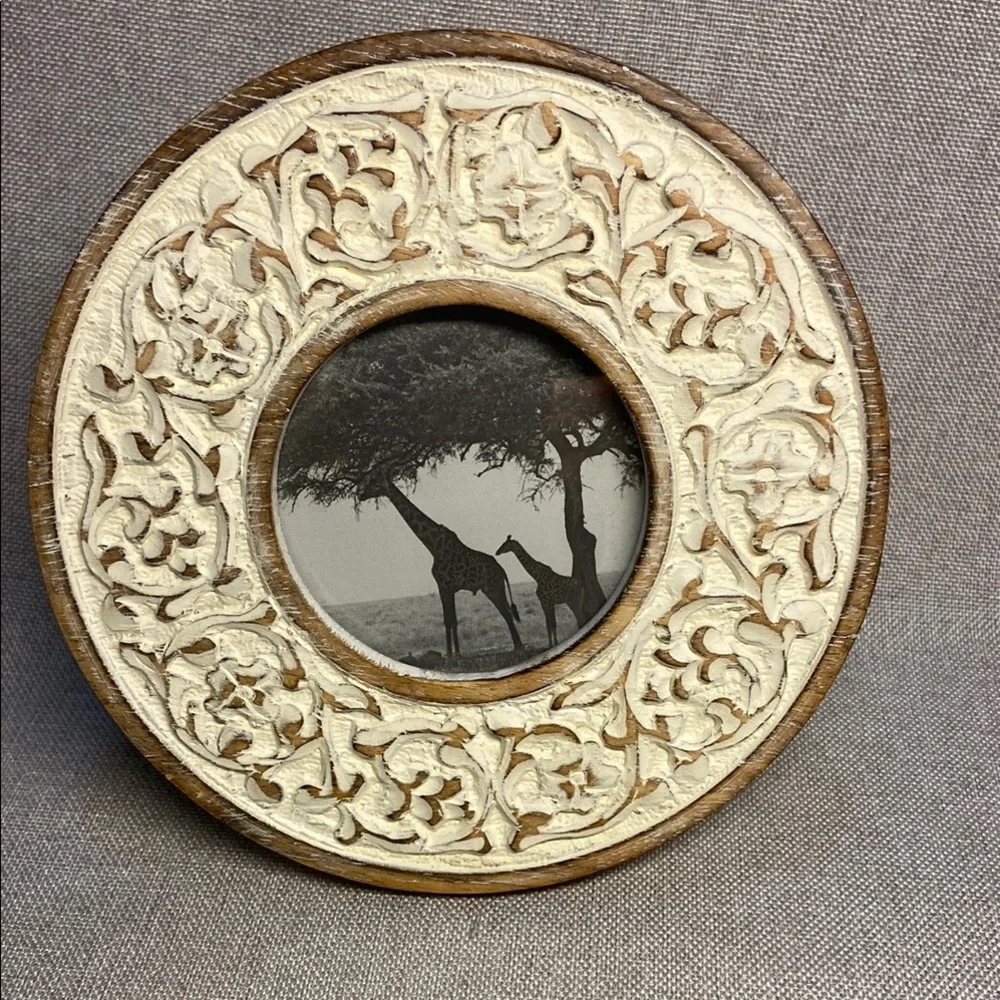 Decorative round, carved wooden picture frame with a distressed white finish.