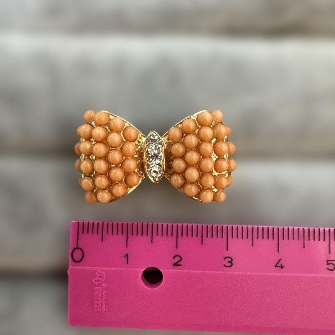 Gold-tone ring with diamond-like white stones and coral-like ribbon shape, size 12